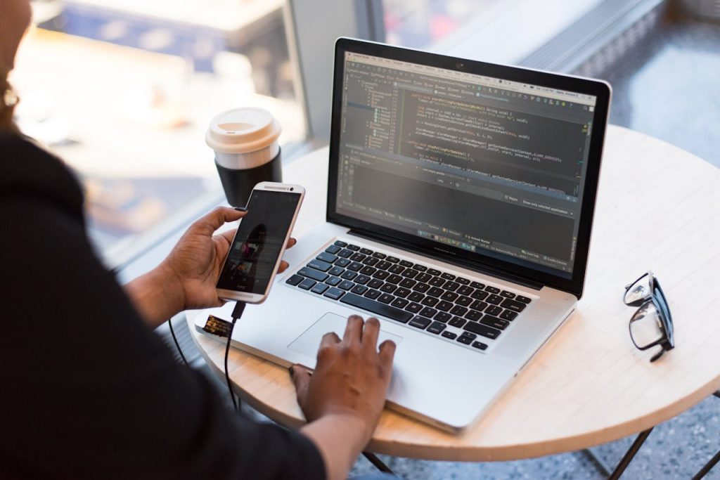 pexels-photo-1181244 Person Holding Smartphone while using Laptop